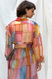 Woman wearing HeenaAgrima's Indradhanush Trench Coat, a colorful, sheer patchwork coat over a white background. 