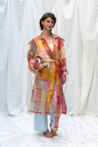 Woman wearing HeenaAgrima's Indradhanush Trench Coat, a colorful, sheer patchwork coat over a white background. 