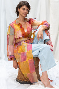 Woman wearing HeenaAgrima's Indradhanush Trench Coat, a colorful, sheer patchwork coat over a white background. 