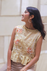 Woman wearing HeenaAgrima's Daffodils Cotton Top, a yellow floral top sitting on a white couch.