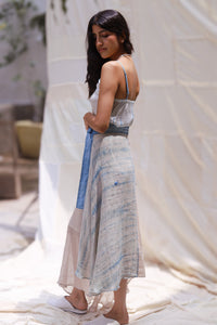 Woman wearing HeenaAgrima's Goa Linen Skirt, a light blue and beige dress with a belt, standing outdoors.