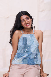 Woman wearing a patchwork tank top against a plain background