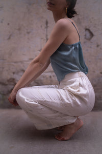 Person wearing a blue top and white pants in a minimalistic setting