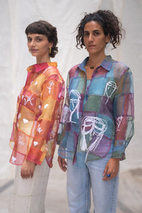 Woman wearing a HeenaAgrima's colorful, patchwork-style shirt, named Stormy against a plain background