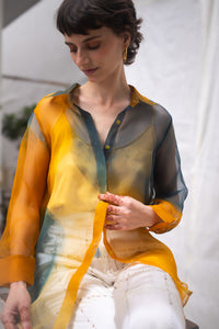 Woman wearing HeenaAgrima's Meadow Silk Organza Shirt, a sheer orange and green Shirt sitting against a white background
