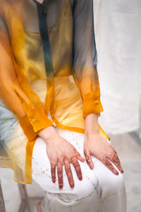 Close-up of a woman wearing HeenaAgrima's Meadow Silk Organza Shirt, a sheer orange and green Shirt sitting against a white background