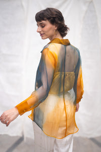 Woman wearing HeenaAgrima's Meadow Silk Organza Shirt, a sheer orange and green Shirt sitting against a white background