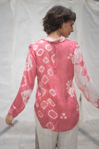 woman wearing a heenaAgrima"s  pink and white naturally tie-dye satin silk shirt against a plain background 