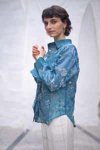 Woman wearing a blue floral patterned shirt, named as Blue Queen's Bagh, made by HeenaAgrima against a neutral background.