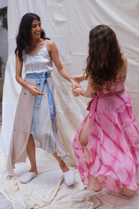 Woman wearing HeenaAgrima's Goa Linen Skirt, a light blue and beige dress with a belt, standing outdoors.