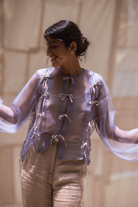 Woman wearing HeenaAgrima's Zoe Lilac Top a sheer top with lace details in front of light curtains