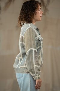 Person wearing HeenaAgrima's Paddy Linen Jacket, a patterned jacket and light blue jeans against a neutral background